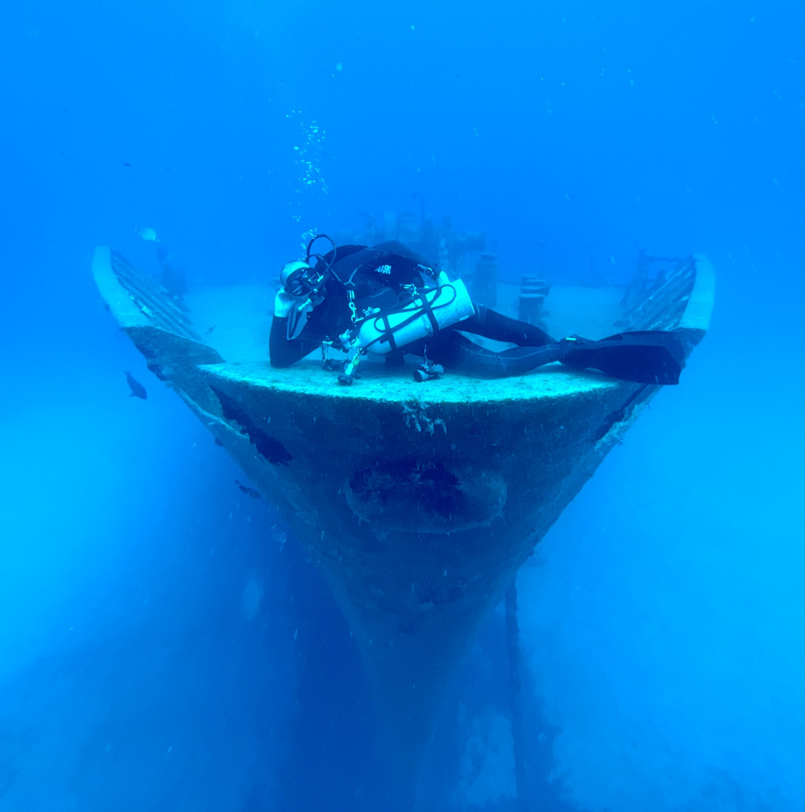 Diver approaching the bow of a large wreck, the hull dropping away below, Malta