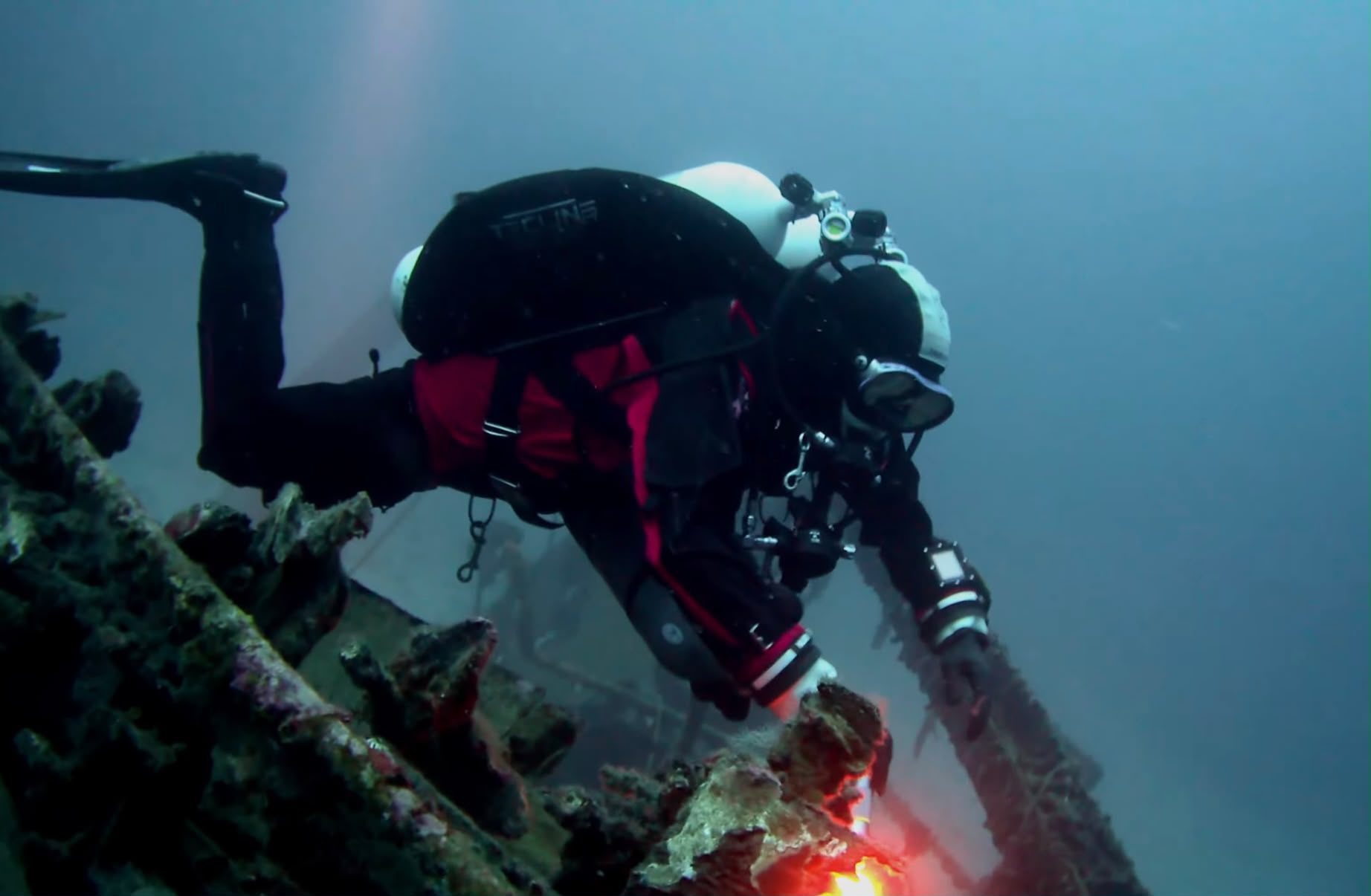 Technical diver with a torch on the Brioni wreck off Vis in Croatia, in low light